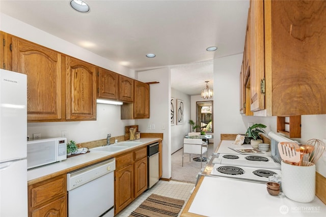kitchen with white appliances, a sink, light countertops, recessed lighting, and brown cabinetry