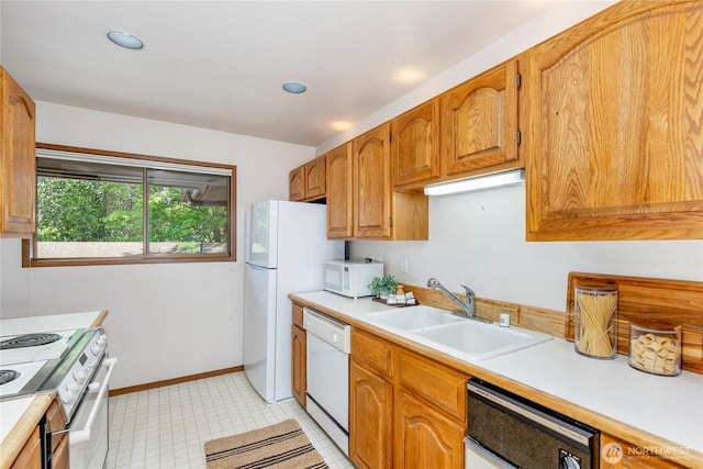 kitchen with white appliances, a sink, light countertops, brown cabinets, and recessed lighting