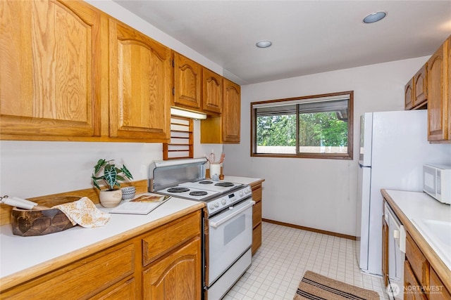 kitchen featuring white appliances, light countertops, brown cabinetry, light tile patterned floors, and recessed lighting