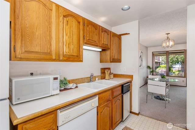 kitchen with white appliances, a sink, light countertops, a chandelier, and light colored carpet