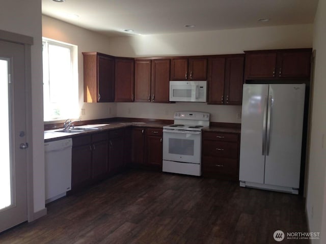 kitchen featuring dark wood-style flooring, a sink, and white appliances