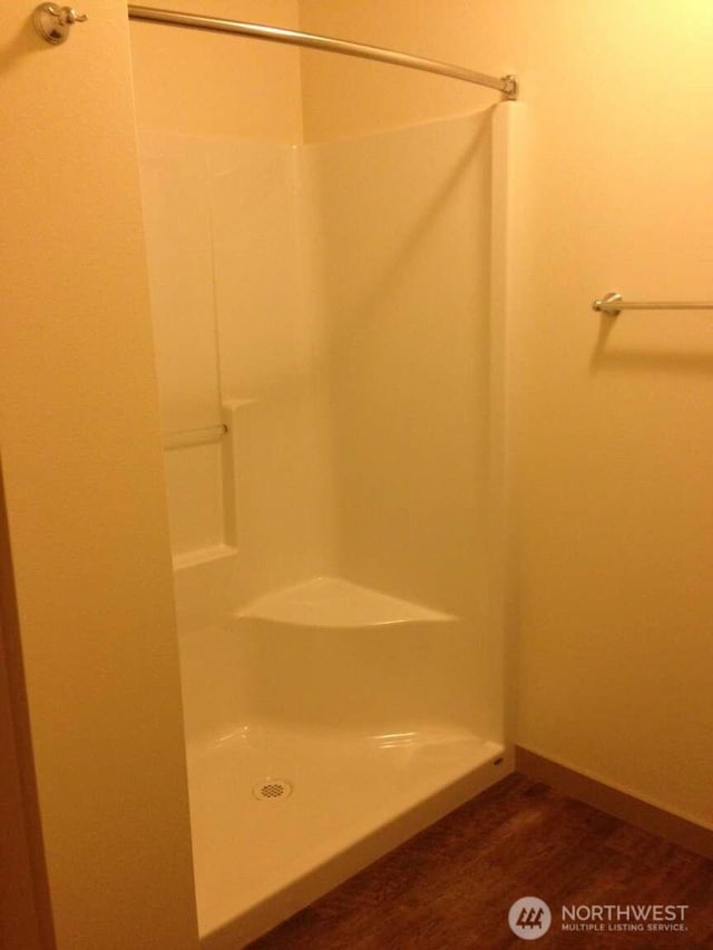bathroom with walk in shower, baseboards, and wood finished floors