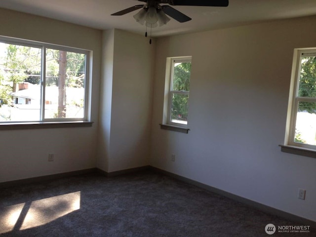 unfurnished room featuring ceiling fan, dark colored carpet, and a healthy amount of sunlight