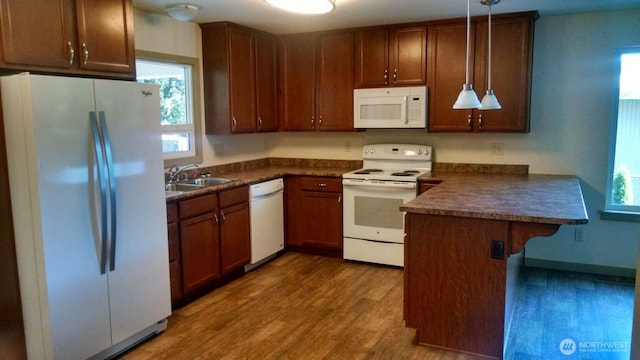 kitchen featuring plenty of natural light, white appliances, a sink, a peninsula, and dark countertops