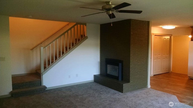 unfurnished living room with a brick fireplace, stairway, ceiling fan, and carpet floors