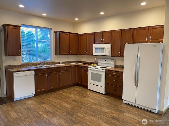 kitchen featuring a sink, white appliances, dark countertops, and dark wood-type flooring