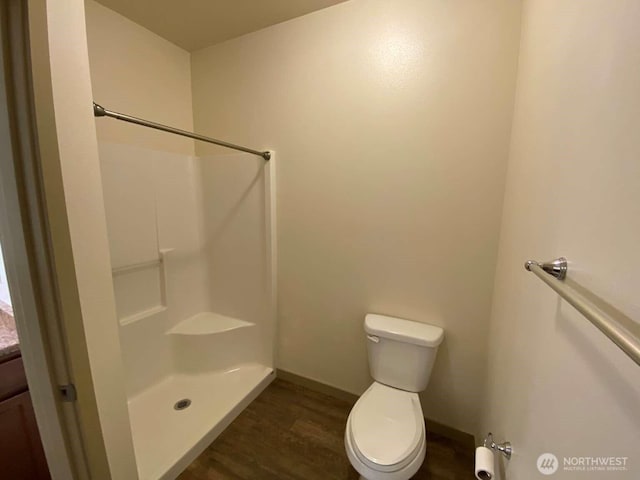 bathroom featuring walk in shower, toilet, baseboards, and wood finished floors