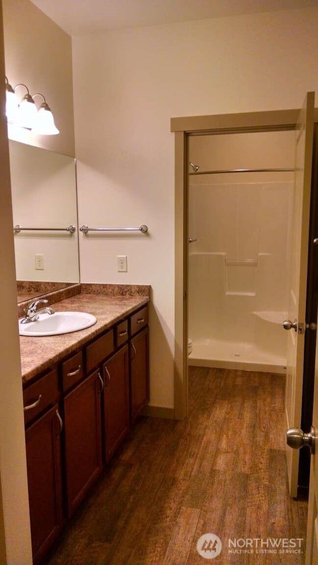 full bath with walk in shower, vanity, and wood finished floors