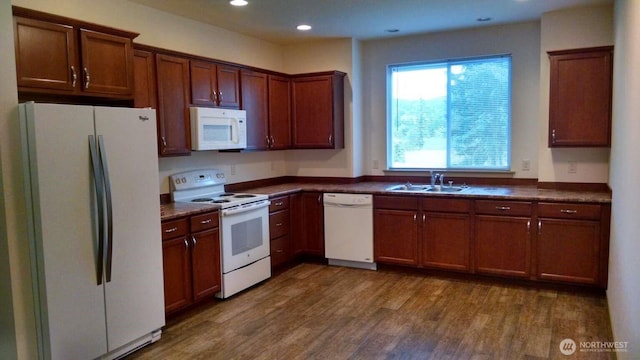 kitchen featuring a sink, dark countertops, dark wood-type flooring, white appliances, and recessed lighting