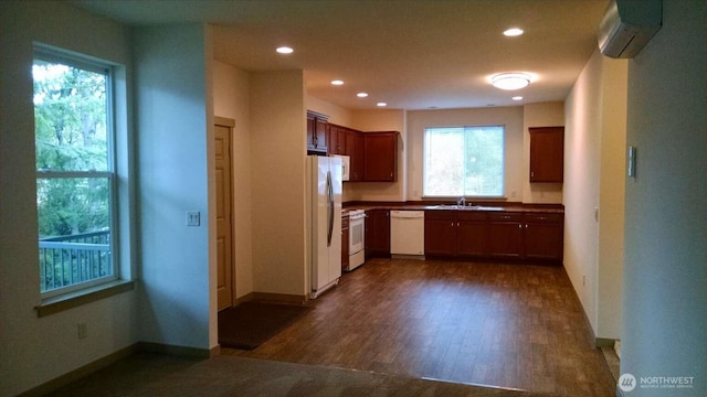 kitchen with recessed lighting, a wall unit AC, white appliances, a sink, and dark wood-style floors