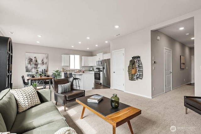living area featuring baseboards, light carpet, and recessed lighting