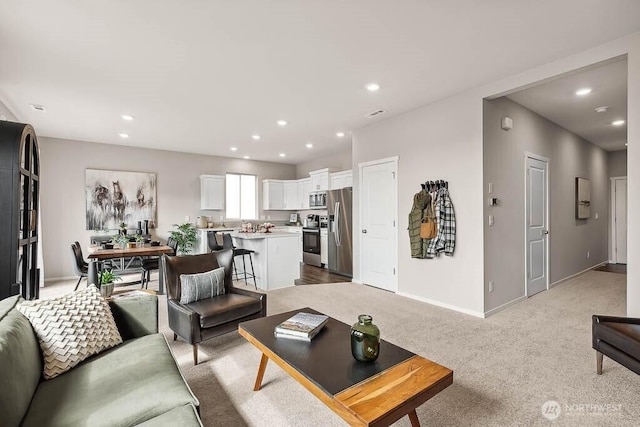 living room featuring baseboards, recessed lighting, and light colored carpet