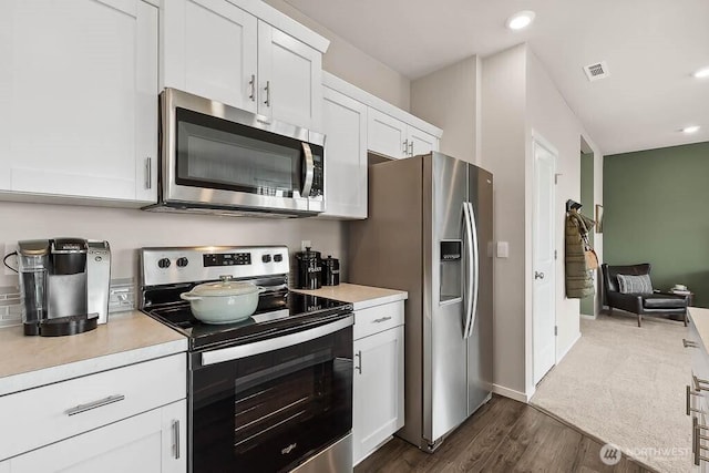 kitchen with white cabinets, light countertops, appliances with stainless steel finishes, and dark wood-style flooring