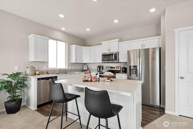 kitchen with a kitchen breakfast bar, light countertops, white cabinets, and appliances with stainless steel finishes