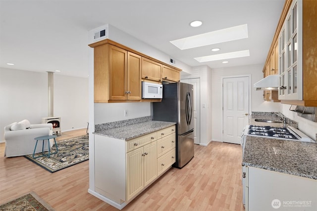 514 Bell St, Edmonds, WA 98020 - kitchen with a wood stove, light wood-style flooring, a skylight, and white microwave
