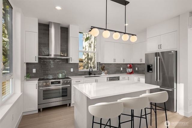1625B 21st Ave, Seattle, WA 98122 - kitchen featuring stainless steel appliances, wall chimney exhaust hood, a sink, a breakfast bar area, and recessed lighting