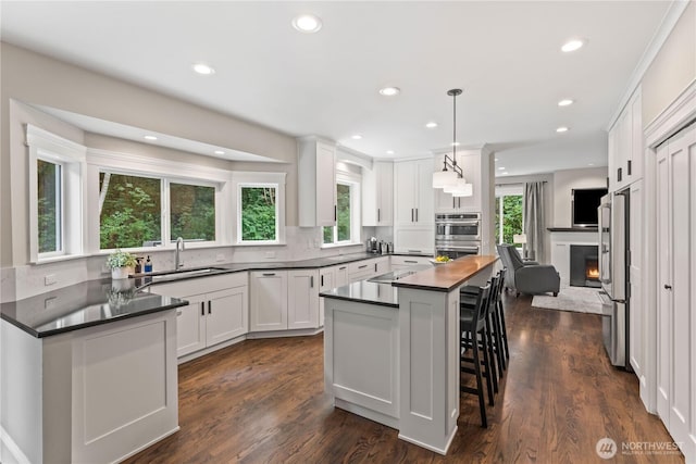 856 Hilltop Ave, Kent, WA 98031 - kitchen featuring dark countertops, a sink, white cabinetry, black electric cooktop, and dark wood-type flooring