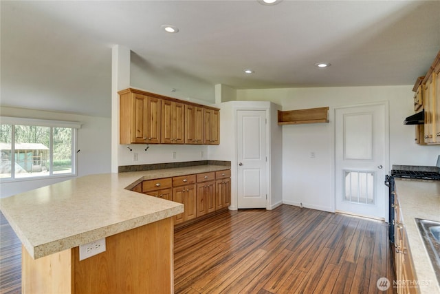 kitchen featuring a peninsula, dark wood-style flooring, light countertops, under cabinet range hood, and recessed lighting
