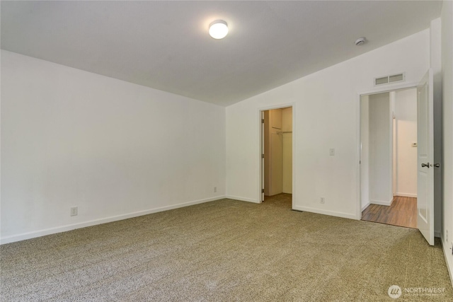 carpeted empty room with vaulted ceiling, baseboards, and a smoke detector