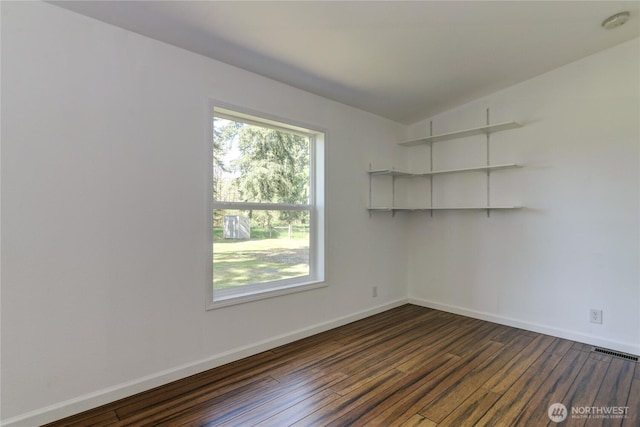 unfurnished room with dark wood-style flooring, baseboards, and a smoke detector