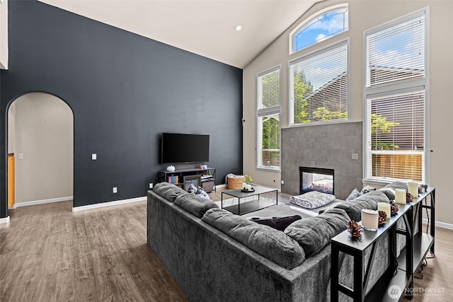 4002 33rd St NE, Tacoma, WA 98422 - living area featuring high vaulted ceiling, wood finished floors, baseboards, arched walkways, and a tile fireplace
