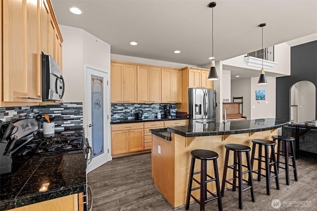 4002 33rd St NE, Tacoma, WA 98422 - kitchen with appliances with stainless steel finishes, light brown cabinetry, dark wood finished floors, backsplash, and a breakfast bar