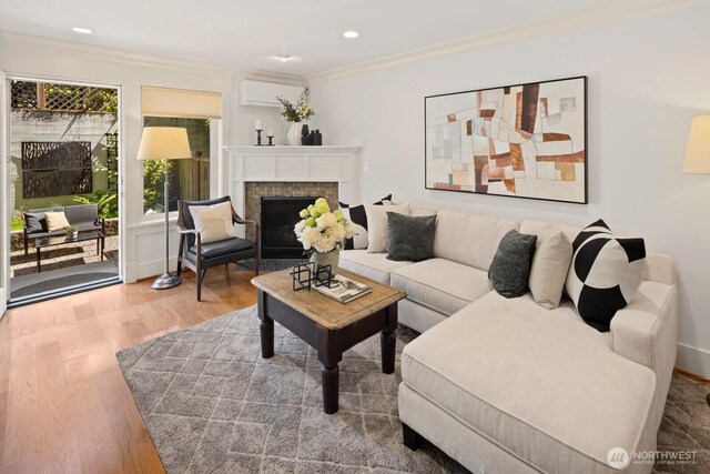living room with wood finished floors, a brick fireplace, ornamental molding, and recessed lighting