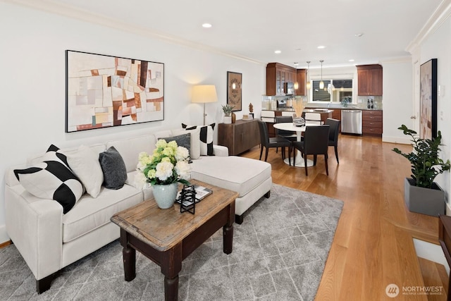 living area featuring ornamental molding, light wood finished floors, and recessed lighting