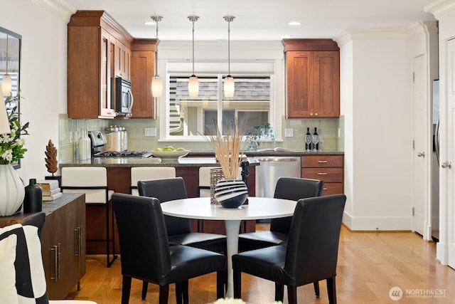 kitchen featuring stainless steel appliances, light wood-style flooring, dark countertops, tasteful backsplash, and brown cabinetry