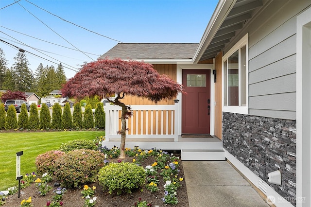 doorway to property featuring a lawn and stone siding