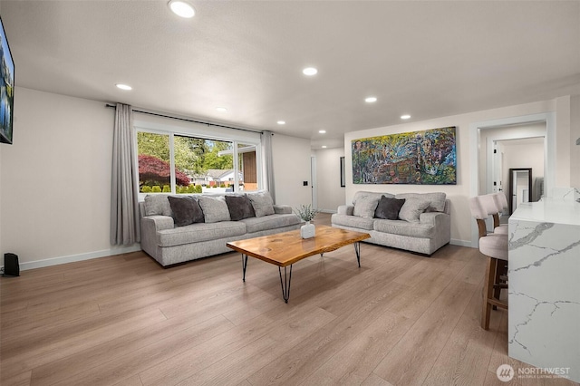 living room with light wood-style floors, recessed lighting, and baseboards