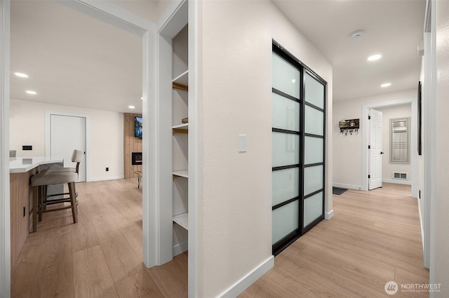 corridor with light wood finished floors, recessed lighting, and baseboards