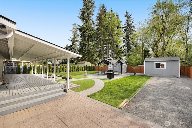 view of yard with an outdoor structure, a deck, a shed, and a patio area
