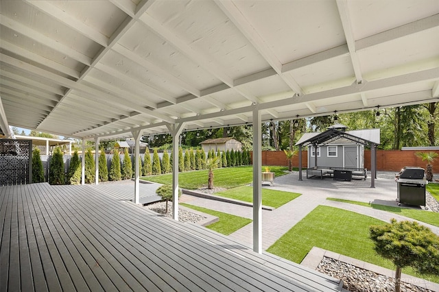 wooden deck featuring a storage unit, an outdoor structure, area for grilling, and a patio area