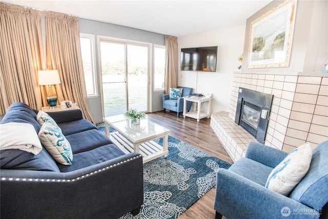living room with a tiled fireplace and wood finished floors