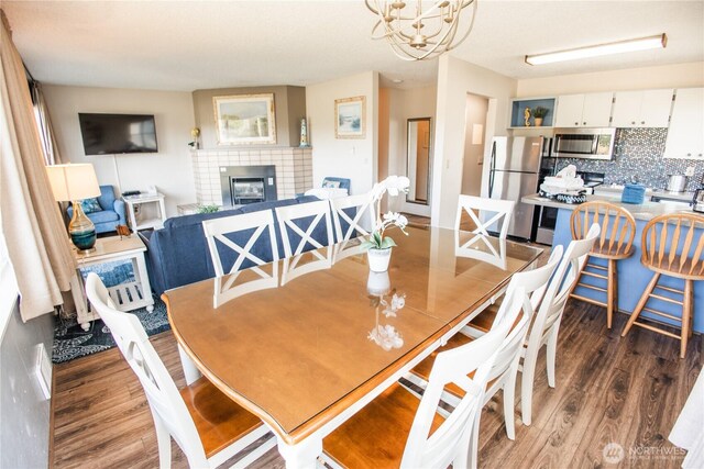 dining area featuring a notable chandelier, a fireplace, and wood finished floors