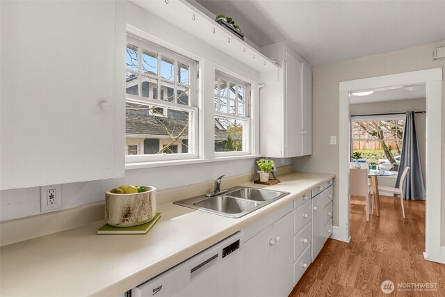 kitchen with dishwasher, a sink, white cabinets, and light countertops
