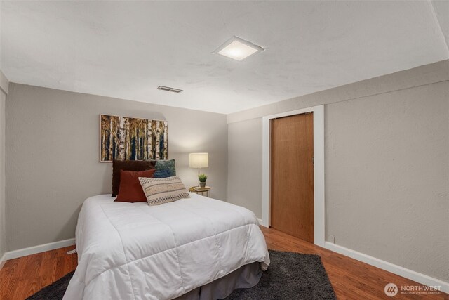 bedroom with wood finished floors, baseboards, and a closet