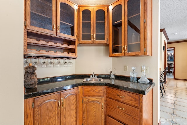 7117 NE 176th Ave, Vancouver, WA 98682 - kitchen featuring glass insert cabinets, light tile patterned flooring, a textured ceiling, brown cabinets, and ornamental molding
