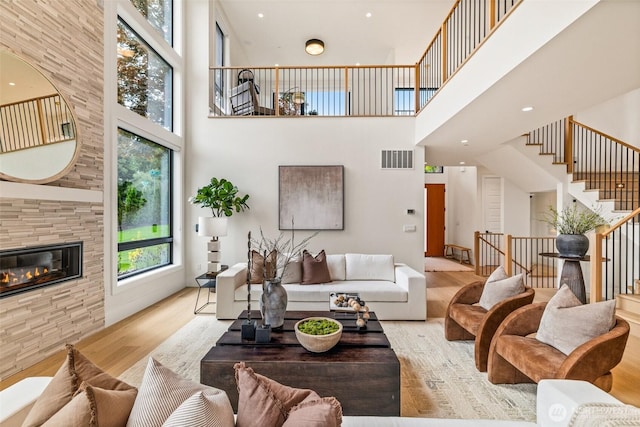 8458 NE 9th St, Medina, WA 98039 - living area with a towering ceiling, wood finished floors, stairs, a large fireplace, and recessed lighting