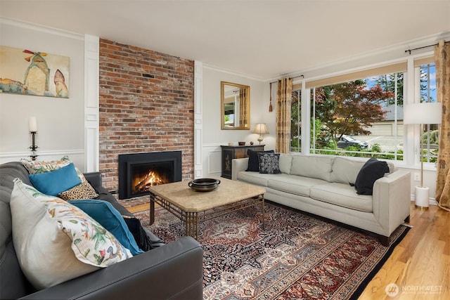 living room featuring a brick fireplace, light wood finished floors, and ornamental molding