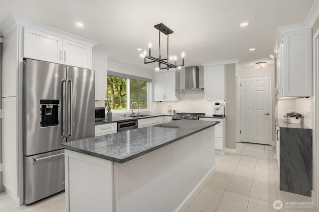 kitchen featuring high end fridge, wall chimney range hood, a sink, tasteful backsplash, and white cabinets