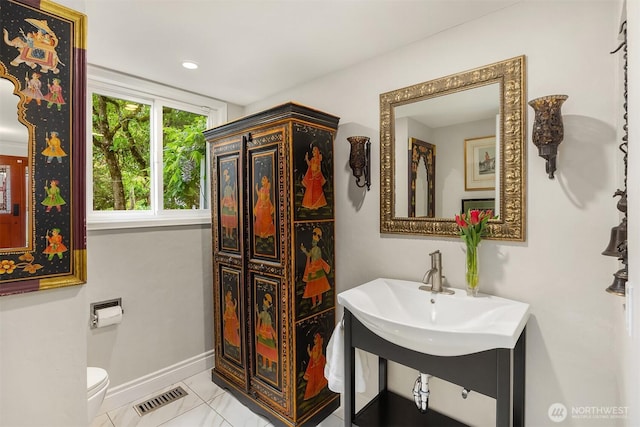 bathroom featuring baseboards, toilet, and a sink