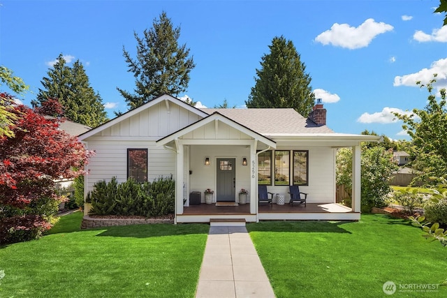 view of front facade featuring board and batten siding, a porch, a chimney, and a front yard