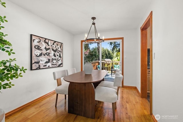 dining space with light wood finished floors, baseboards, and a notable chandelier