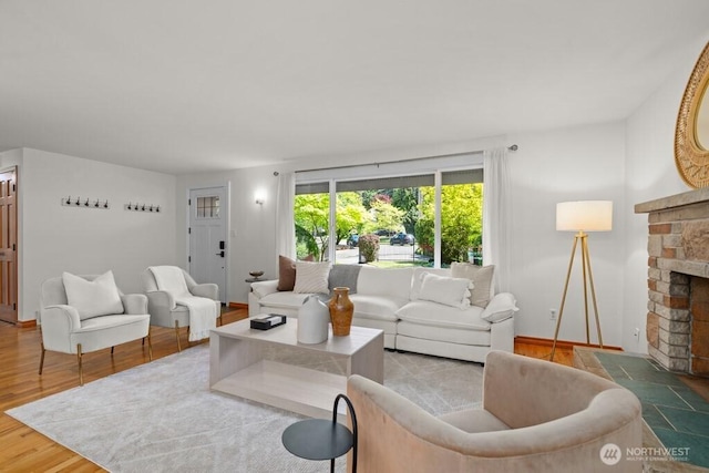 living room with baseboards, a fireplace with raised hearth, and wood finished floors