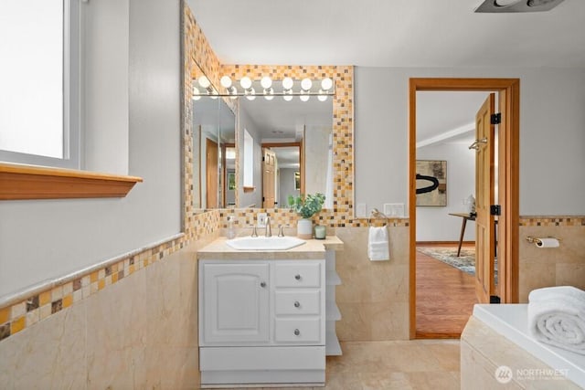 bathroom with tile walls, tile patterned floors, vanity, and a wainscoted wall