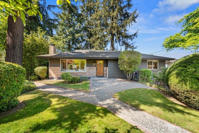 ranch-style home with brick siding, a chimney, and a front yard