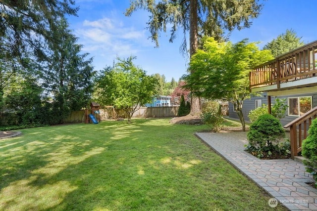 view of yard with a fenced backyard, a patio area, a deck, and a playground