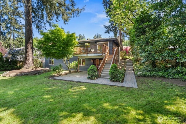 rear view of house featuring stairway, a wooden deck, a patio, and a lawn